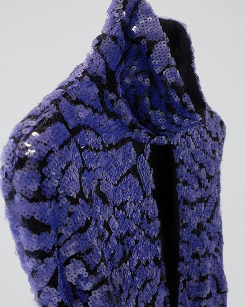 Close-up of a purple and black sequin fabric on a plain background
