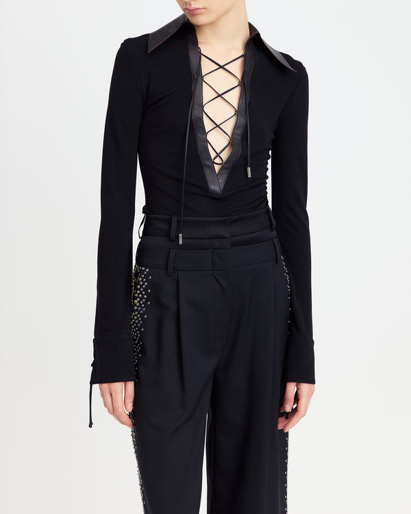 16Arlington Pia top with black smooth jersey, featuring a plunging V-neckline framed by a brown leather pointed collar with branded metal-tipped cord lacing. This refined piece brings modern tailoring to everyday and party looks from a luxury British designer brand. - close-up